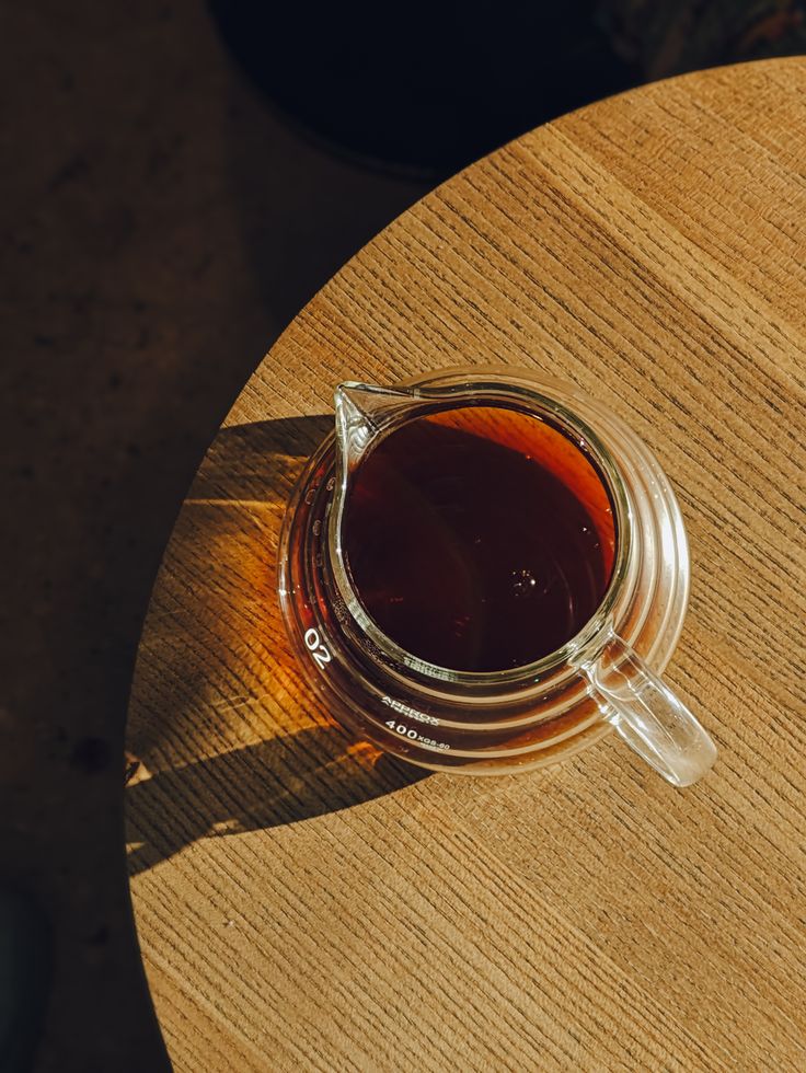 Brewed Peru Gesha coffee in a glass server on a wooden table